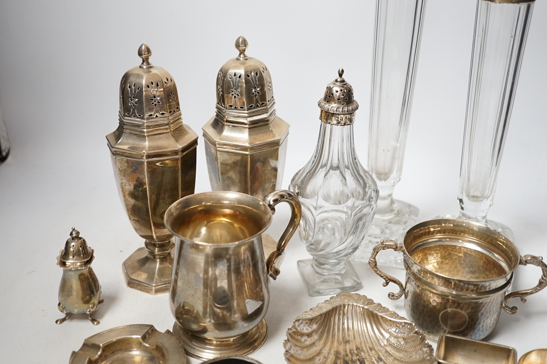 Assorted small silver including a christening mug, a planished porringer, pair of George V sugar casters, butter shell, ashtray, two mounted glass posy vases, four condiments, four napkin rings, a mounted glass cruet bot